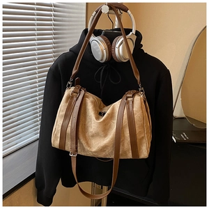 Detail view of khaki canvas tote bag featuring brown leather straps and metal buckles