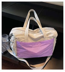 Detail of grey nylon travel tote featuring a vibrant purple plaid pocket and large capacity