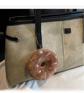 Dettaglio del ciondolo a ciambella di cioccolato appeso a una borsa tote beige