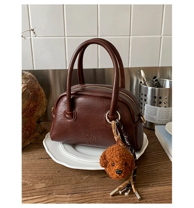 Detailed view of deep brown bowling bag with bear charm and enjoy each day text