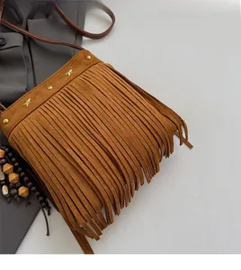 Détail d'un sac bandoulière en daim marron avec de longues franges et clous dorés