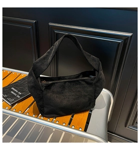 Gros plan d'un sac hobo noir mat avec fermeture éclair dorée sur un banc industriel