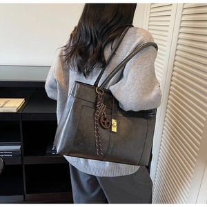 Détail du sac cabas en cuir mat vintage avec fermoir métallique et pendentifs décoratifs
