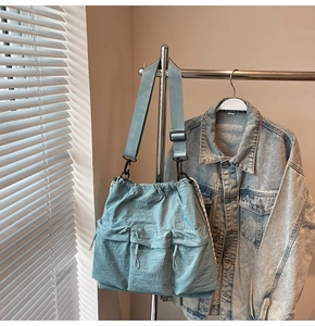 Detail of light blue nylon crossbody bag with drawstring closure and three front pockets