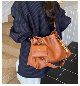 Detail view of brown vintage bucket bag with ethnic charms and mini coin pouch accessory