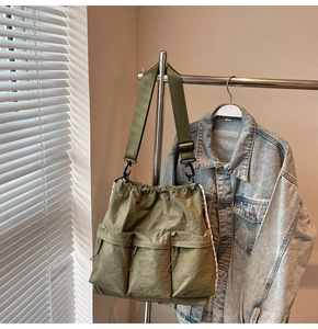 Detail of olive green nylon crossbody bag with multi-pocket design and adjustable strap