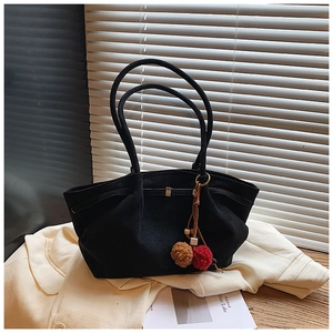 Gros plan sur un sac cabas noir mat avec des breloques décoratives en pompon