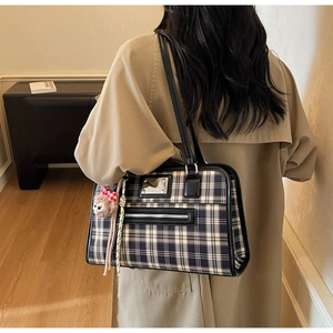 Detail of blue and white checkered tote bag with leather straps and plush lamb charm