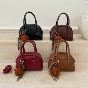 Detail view of four bowling bags in black, brown, and wine red with plush bear charms