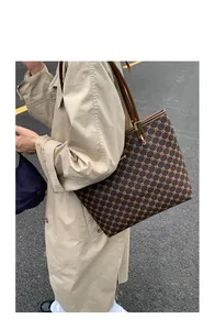 Detail view of large dark brown tote bag with classic pattern and gold hardware