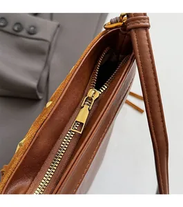 Détail de la fermeture éclair dorée mate sur le sac seau en cuir marron et daim mixte