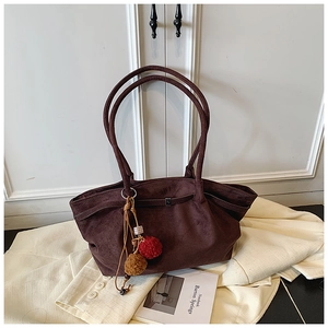 Détail du sac cabas en daim marron foncé avec pompon décoratif et perles en bois