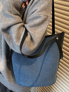 Fashionable denim tote bag with black leather handles and spacious bucket design
