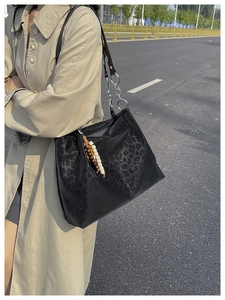 Close-up of black leopard print tote bag with metal chain strap and wood bead tassel charm