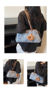 Dettaglio borsa a spalla in denim azzurro con finiture in pelle marrone e ciondolo a ciambella