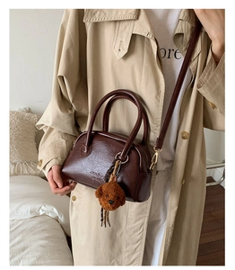Detail of dark brown leather bowling bag with vintage texture and cute teddy charm