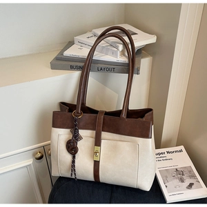Détail du sac cabas rétro bicolore avec fermoir en métal, texture cuir fin et pendentif
