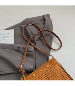 Détail du sac bandoulière en daim marron avec clous étoilés dorés et longues franges