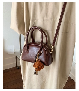 Detail view of dark brown bowling bag with teddy bear pendant and onio brand embossing