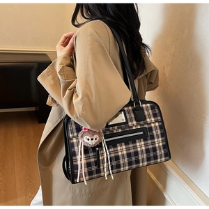 Classic blue plaid tote bag with black leather trim and plush charm worn with trench coat