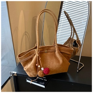 Détail d'un cabas en daim marron avec boucle métallique et breloque pompon colorée