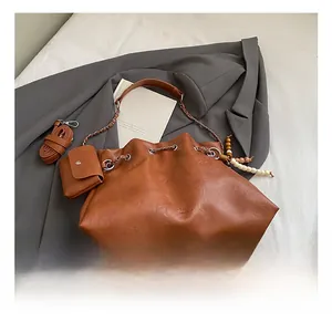 Detail of retro brown leather bag with lychee texture and ethnic wooden bead charm