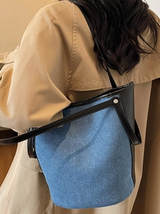 Stylish large denim bucket bag for women featuring black leather trim and silver studs