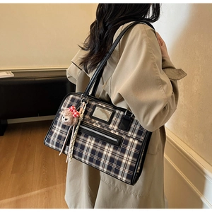 Detail shot of tricolor plaid tote bag with silver zipper pocket and plush alpaca charm