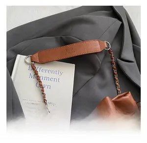 Close-up of brown leather bucket bag with silver chain and wide embossed handle