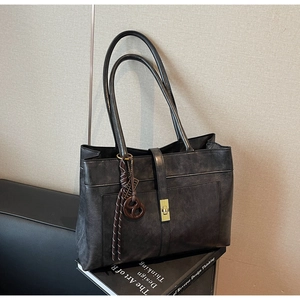 Détail d'un grand sac cabas en cuir mat gris foncé avec fermoir en métal et décor