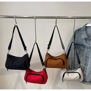 Detail showing colorful nylon crossbody bags with curved zip pockets and adjustable straps