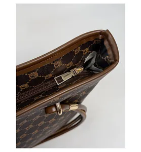Close-up of the smooth zipper and durable leather trim on this brown checkered tote bag