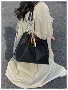 Close-up of black leopard embossed tote with silver chain and colorful beaded tassel