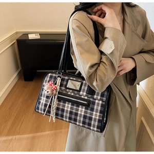 Detail of vintage plaid tote bag featuring front zipper pocket and red bear charm accessory