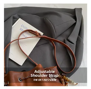 Detail of adjustable leather strap and cinch closure on a brown leather bucket bag