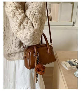 Close-up of brown vintage Boston bag featuring a plush bear charm and metallic zipper details