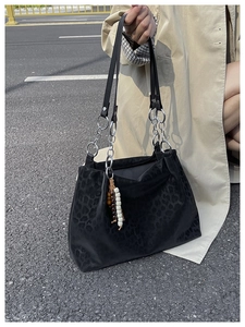 Street view of black leopard print tote bag with silver chain and beaded charm
