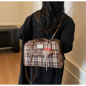 Close-up of vintage brown plaid tote bag featuring a plush charm and leather handle