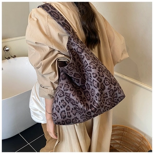 Detail view of large leopard print tote bag worn over the shoulder in a minimalist room