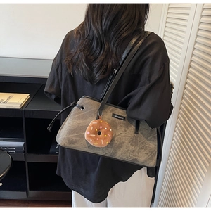 Dettaglio borsa tote grigia lavata con patch logo e ciondolo a forma di ciambella