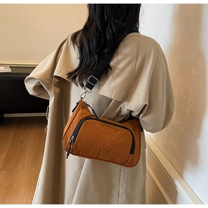Detailed back view of a brown nylon crossbody bag with BIFW embroidery on a model