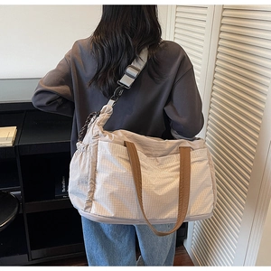 Close-up of a large grey tote travel bag featuring wide comfort shoulder straps and drawstrings
