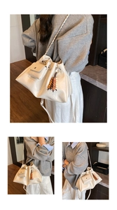 Detailed view of cream drawstring bucket bag with wooden bead charm and mini front pocket