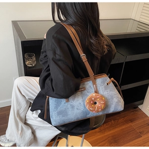 Borsa tote in denim blu con tracolla in pelle marrone e ciondolo a forma di ciambella