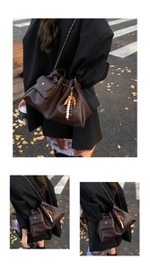 Close-up of brown leather shoulder bag with metal chain strap and decorative beaded pendant