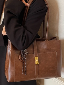 Sac fourre-tout en cuir marron avec fermoir doré et accessoire tressé tendance
