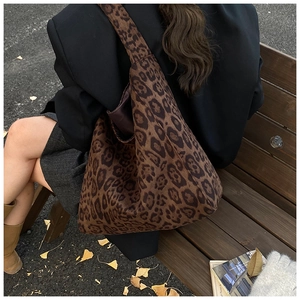 Close-up of leopard print tote bag being worn by a model in a natural outdoor autumn park setting