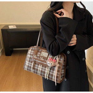 Detail of vintage plaid tote bag with brown leather handles and plush bear charm
