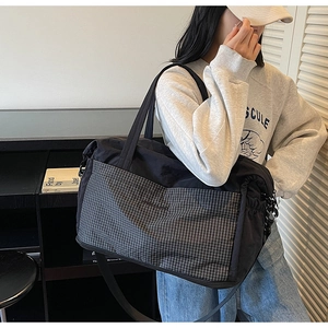 Detail view of large travel tote with black and white plaid pocket and adjustable strap