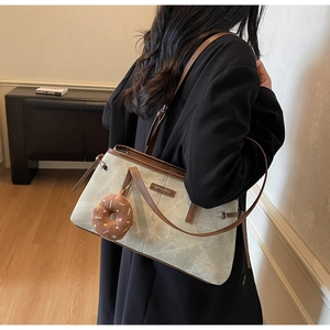 Dettaglio della borsa tote grigio-verde con spalline in pelle marrone e ciondolo